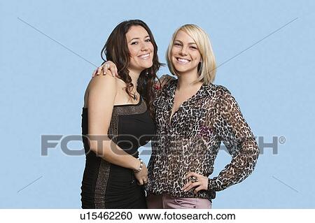 Stock Image - Portrait of two beautiful multi ethnic women smiling over blue background. Fotosearch