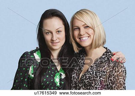 Stock Photo - Portrait of two beautiful young women smiling over blue background. Fotosearch