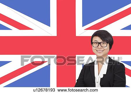 Stock Image - Portrait of young businesswoman smiling over British flag. Fotosearch