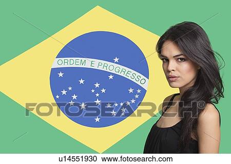 Stock Image - Portrait of young woman against Brazilian flag. Fotosearch