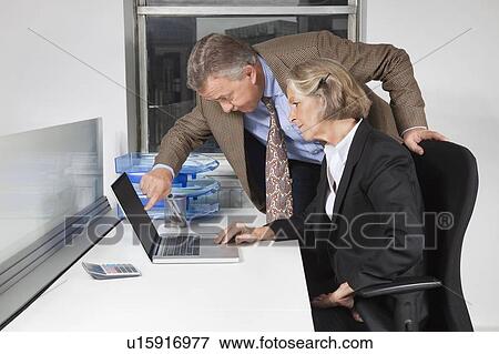 Side view of businesswoman and man looking at laptop screen at desk in office View Large Photo Image Stock Photo - Side view of businesswoman and man looking at laptop screen at desk in office. Fotosearch