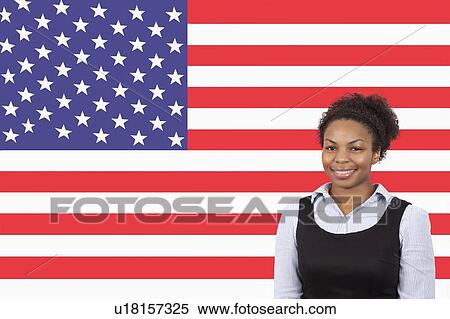 Stock Photography - Young African American businesswoman smiling over American flag. Fotosearch