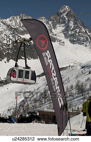 Stock Image - Aerial tramway and banner at Les Grands Montets ski area, Mont Blanc, Chamonix, Rhone-Alpes, France. Fotosearch