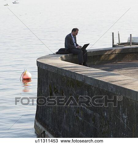 Man using a laptop at the riverside, District 2, Zurich, Switzerland View Large Photo Image Stock Image - Man using a laptop at the riverside, District 2, Zurich, Switzerland. Fotosearch