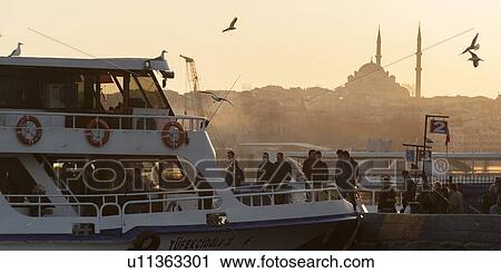 Stock Image - Tourists boarding a ferry with Suleymaniye Mosque in the background, Istanbul, Turkey. Fotosearch