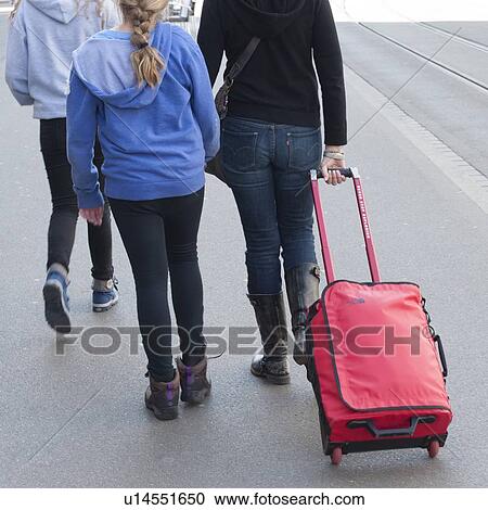 Stock Image - Tourists walking with luggage on a street, District 2, Zurich, Switzerland. Fotosearch