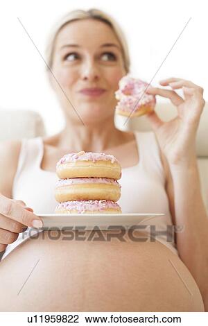 Pregnant woman eating doughnuts View Large Photo Image Stock Image - Pregnant woman eating doughnuts. Fotosearch