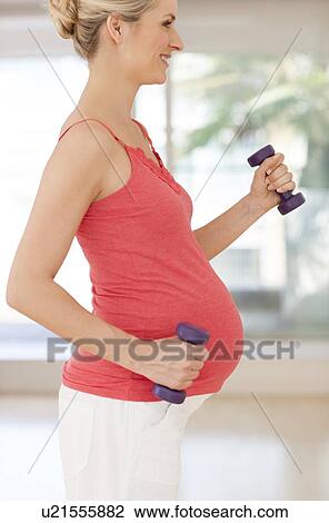 Stock Image - Pregnant woman lifting weights. Fotosearch