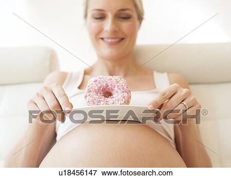 Stock Photo - Pregnant woman with doughnuts. Fotosearch