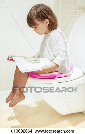 Picture - Toddler reading on the toilet. Fotosearch