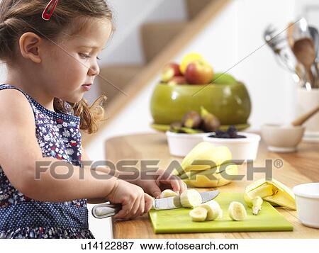 Young girl cutting a banana View Large Photo Image Stock Photo - Young girl cutting a banana. Fotosearch