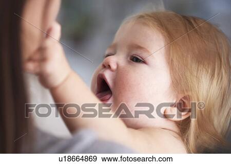 Baby girl reaching for mothers face View Large Photo Image Stock Photo - Baby girl reaching for mothers face. Fotosearch