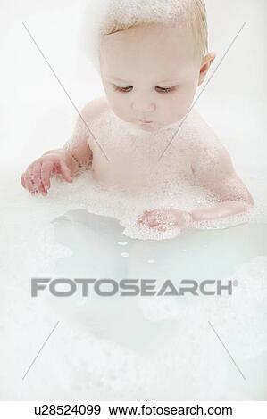 Stock Photo - Baby girl sitting in bathtub. Fotosearch