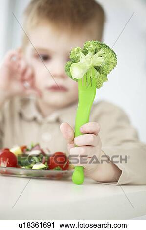 Stock Image - Boy examining forkful of broccoli. Fotosearch