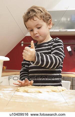 Stock Photograph - Boy kneading dough in kitchen. Fotosearch