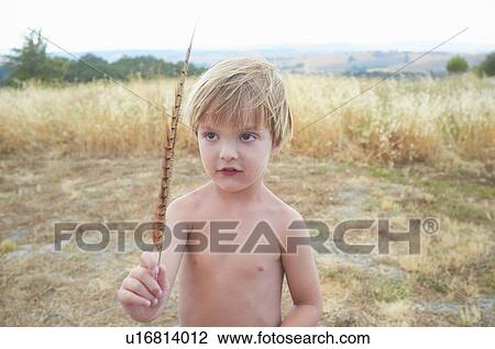 Stock Image - Boy playing with feather in field. Fotosearch