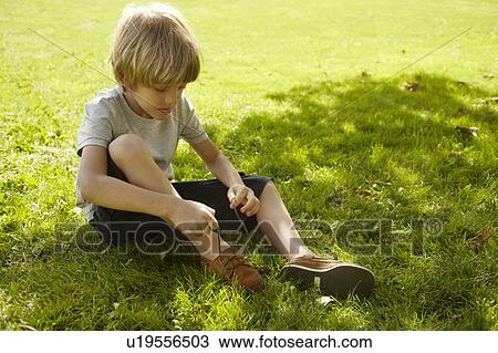 Boy tying his shoe in grass View Large Photo Image Stock Image - Boy tying his shoe in grass. Fotosearch