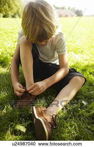 Boy tying his shoe in grass View Large Photo Image Stock Image - Boy tying his shoe in grass. Fotosearch
