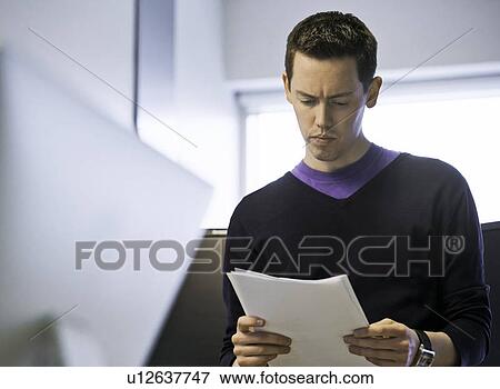 Businessman reading papers in office View Large Photo Image Stock Photo - Businessman reading papers in office. Fotosearch
