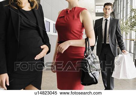 Stock Photography - Businessman watching colleagues in lobby. Fotosearch