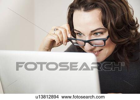 Picture - Businesswoman using laptop at desk. Fotosearch