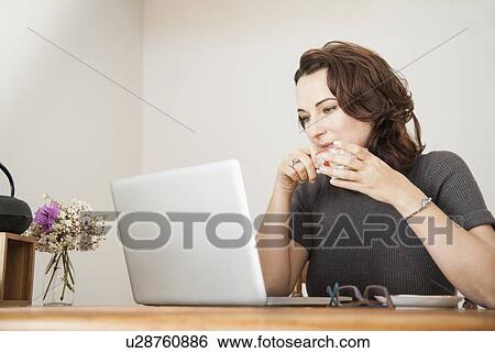 Stock Photograph - Businesswoman using laptop at desk. Fotosearch