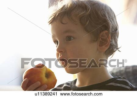 Stock Image - Close up of boy eating apple. Fotosearch