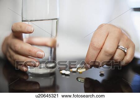 Stock Image - Close up of woman taking vitamins. Fotosearch