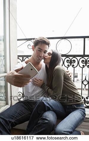Stock Photo - Couple taking pictures in windowsill. Fotosearch