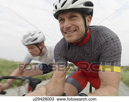 Stock Image - Father and son cycling on rural road. Fotosearch
