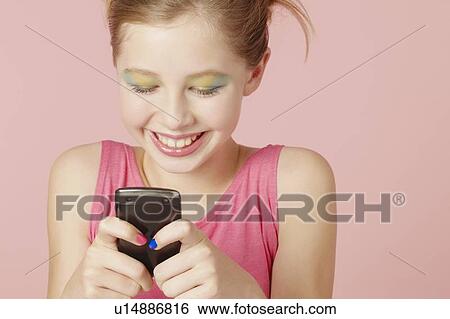 Stock Photograph - Girl in colorful makeup using cell phone. Fotosearch