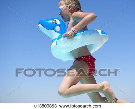 Stock Image - Girl jumping in inflatable ring. Fotosearch