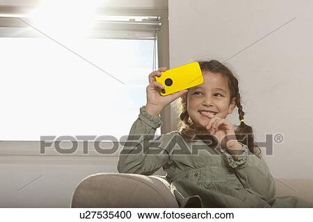 Girl playing with cell phone on sofa View Large Photo Image Stock Image - Girl playing with cell phone on sofa. Fotosearch