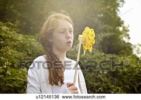 Stock Photograph - Girl playing with pinwheel outdoors. Fotosearch