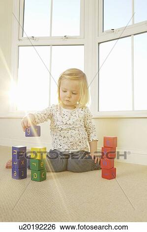 Girl playing with toy blocks on floor View Large Photo Image Stock Photograph - Girl playing with toy blocks on floor. Fotosearch