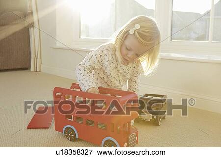 Stock Photo - Girl playing with toy bus on floor. Fotosearch