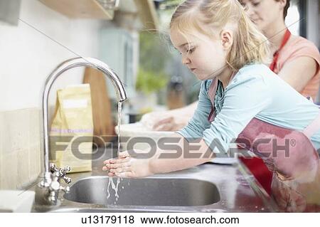 Girl washing her hands in kitchen View Large Photo Image Stock Photo - Girl washing her hands in kitchen. Fotosearch
