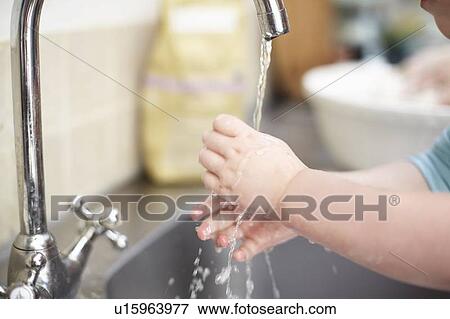 Stock Photo - Girl washing her hands in kitchen. Fotosearch