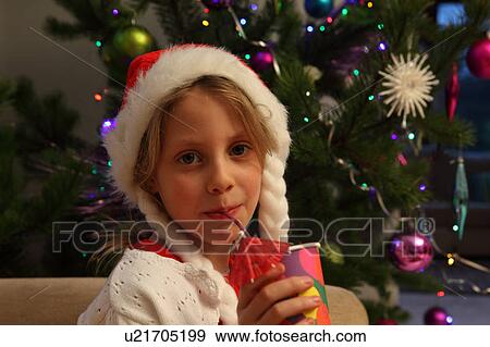 Girl wearing Santa hat by Christmas tree View Large Photo Image Stock Photo - Girl wearing Santa hat by Christmas tree. Fotosearch