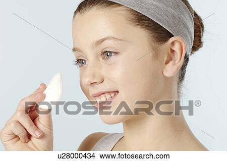 Picture - Girl wiping her face with cotton pad. Fotosearch