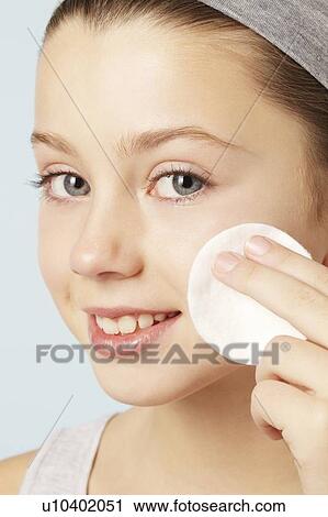 Stock Image - Girl wiping her face with cotton pad. Fotosearch