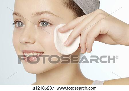 Stock Photo - Girl wiping her face with cotton pad. Fotosearch