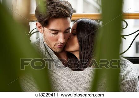 Stock Image - Kissing couple wrapped in blanket . Fotosearch