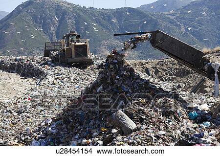 Picture - Machinery dumping waste in landfill. Fotosearch