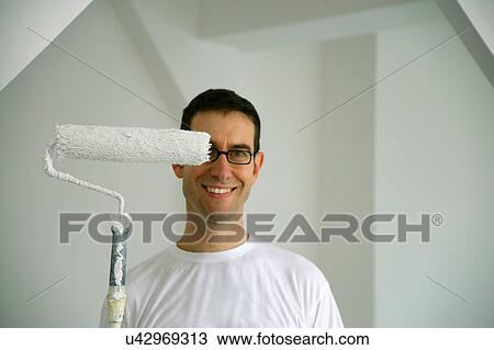 Man holding paint roller in new house View Large Photo Image Stock Image - Man holding paint roller in new house. Fotosearch