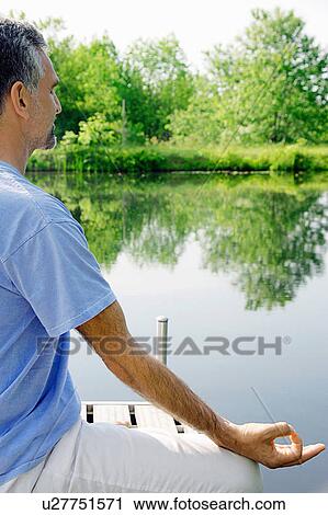 Man meditating on wooden pier View Large Photo Image Stock Image - Man meditating on wooden pier. Fotosearch