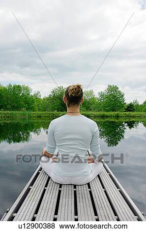 Man meditating on wooden pier View Large Photo Image Stock Photo - Man meditating on wooden pier. Fotosearch