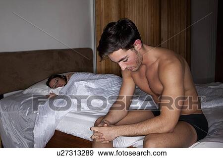 Man sitting in bed with sleeping wife View Large Photo Image Stock Photo - Man sitting in bed with sleeping wife. Fotosearch