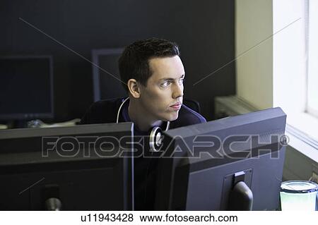 Stock Photo - Man using computers at desk. Fotosearch