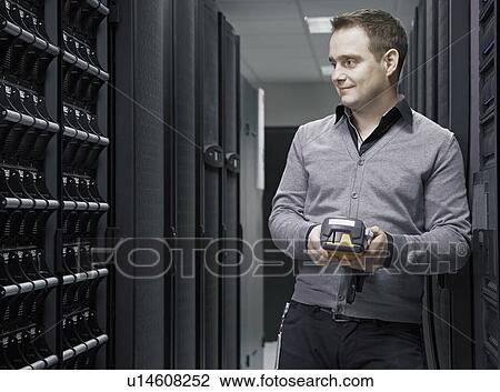 Stock Image - Man working in server room. Fotosearch